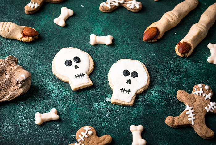 Halloween cookies shaped like skulls, bones, and gingerbread zombies on a green background