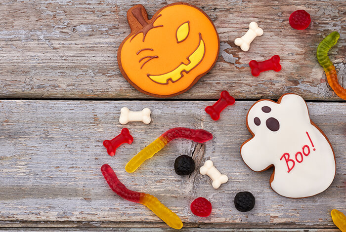 Halloween-themed cookies and candies arranged on a wooden surface