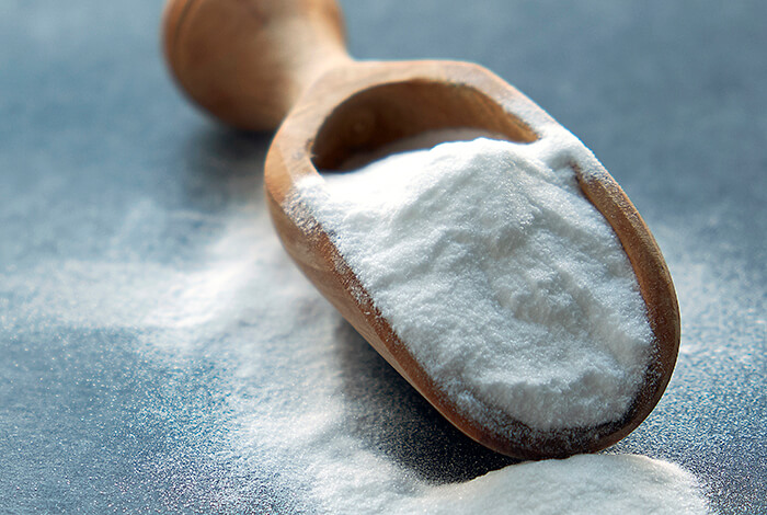 a wooden spoon filled with white baking soda powder