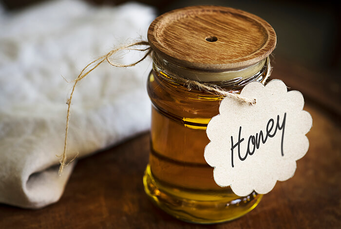 a glass honey jar with a wooden lid and 