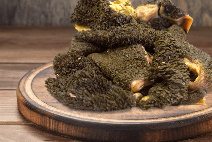 green tripe placed on a wooden chopping board