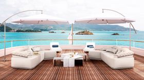 Outdoors | outdoor living area with Anguis curvy sofa, Mayer white marble center table, parasol, and brown wood flooring