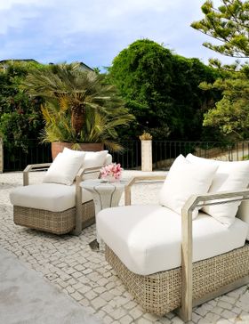 Outdoors | outdoor garden area with Hampton cosy rattan armchair, Suspicion marble side table, cushion, and stone flooring