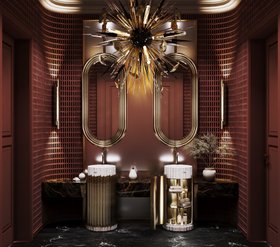 Bathroom | deep red paint luxury bathroom in dark marble finishes with Symphony white pedestal sink and cabinet for storage, Colosseum curvy gold wall mirror, Outbust chandelier, Cyrus wall lamp, and vase