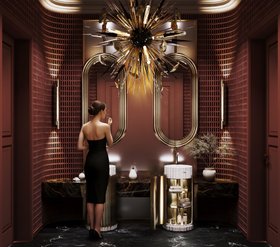 Bathroom | deep red paint luxury bathroom in dark marble finishes with Symphony white pedestal sink and cabinet for storage, Colosseum curvy gold wall mirror, Outburst chandelier, Cyrus wall lamp, and vase