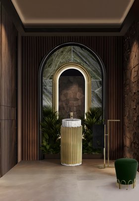 Bathroom | nature inspired bathroom in gold details with Symphony pedestal sink, Colosseum curvy wall mirror, Eden towel rack, Nui deep green stool, floral ornaments, marble flooring, and wood wall panel