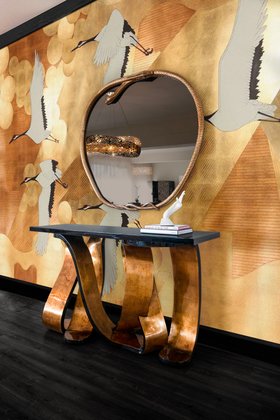 Entryway | nature inspired hallway decor with Ribbon broken gold metallic leaf console, Serpentine apple-shaped wall mirror, wallpaper in animal print style, and dark wood flooring