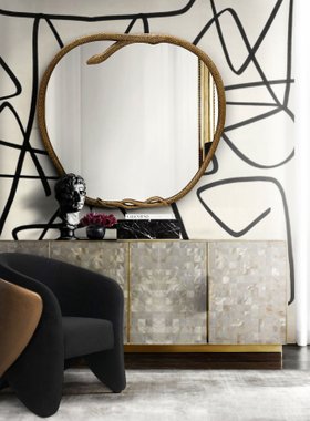 Living Room | autumn/winter reading corner in cosy elegant style with Serpentine gold wall mirror, Denise curvy dark armchair, cabinet for storage, and black and white wallpaper