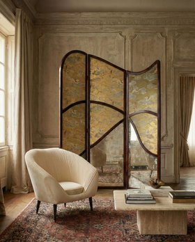 Living Room | cosy elegant reading corner in antique style with Audrey curvy white armchair, Simone glass and walnut wood screen, center table, arabic rug, and curtain