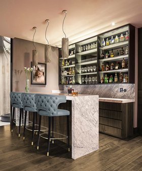 Bar | white marble bar area in mid century modern style with Kansas curvy blue bar chair, Brubeck retro gold pendant lamp, shelves for storage, and brown wood flooring