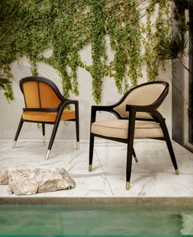 Outdoors | outdoor pool area with Arendal curvy orange, dark, and beige chair in retro style, white marble flooring, stone, and some greenery