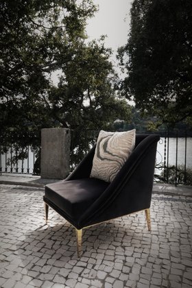 Outdoors | outdoor garden area with Geisha curvy dark chair in velvet, cushion, stone flooring, and some greenery