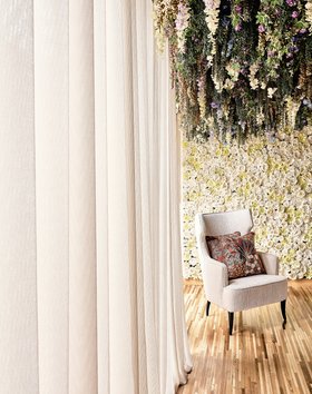 Living Room | spring/summer reading corner in nature inspired style with Iguazu curvy white armchair, cushion, curtain, flower motifs, and wood flooring