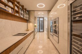 An Upscale Apartment in India | white marble and brown wood kitchen with multiple storage compartments and household appliances