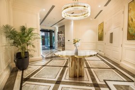 An Upscale Apartment in India | luxury modern hallway with Fortuna gold table, Liberty Slim crystal suspension lamp, Pixel cabinet for storage, vase, and marble flooring