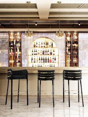 Bar | luxury modern bar area in art deco style with Dunaway curvy dark bar chair, Burj gold pendant lamp, and marble flooring