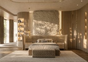 Bedroom | neutral master bedroom in luxury modern style with Charla XL bed, bedside table, ottoman, Hera gold pendant lamp, neutral rug, shelves for storage, stone wall, and wood flooring