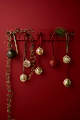 Ib Laursen – Zederngirlande mit Weihnachtskugeln vor roter Wand, Stimmungsbild