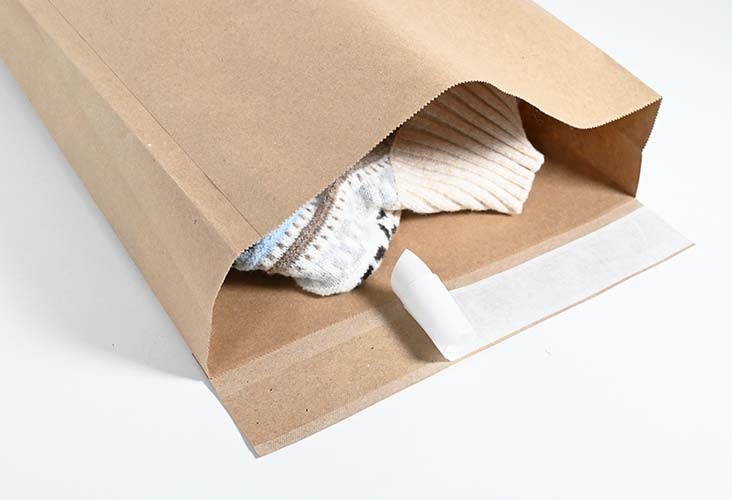 Side gusset paper mailing bag expanded at both sides, packed with folded clothing