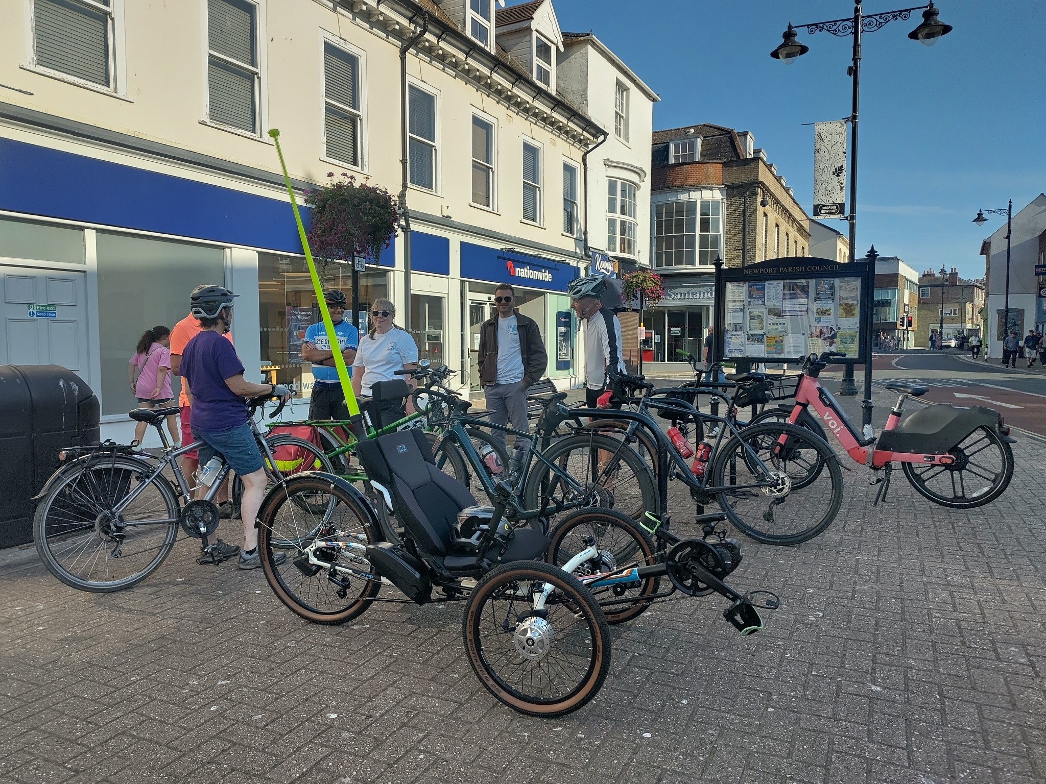 a cycle rack overflowing with a variety of bicycles including a ICE recumbent trike, a brompton, a long tail cargo bike and a rental Voi as well as some more normal looking drop bar bikes
