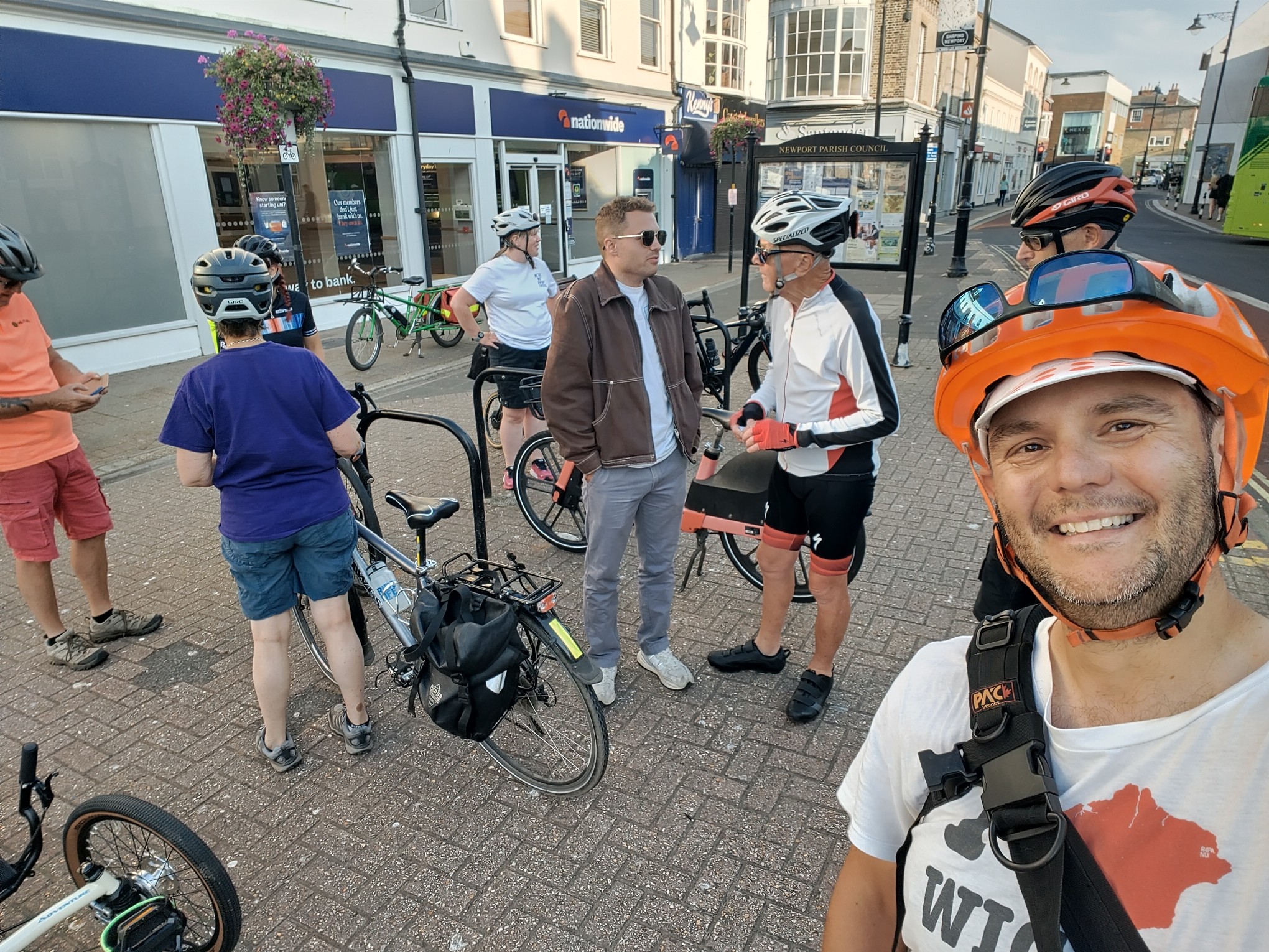 a selfie of the poster wearing a I (isle of wight) Wight t-shirt and lots of people who have just finished riding bikes chatting in a town square