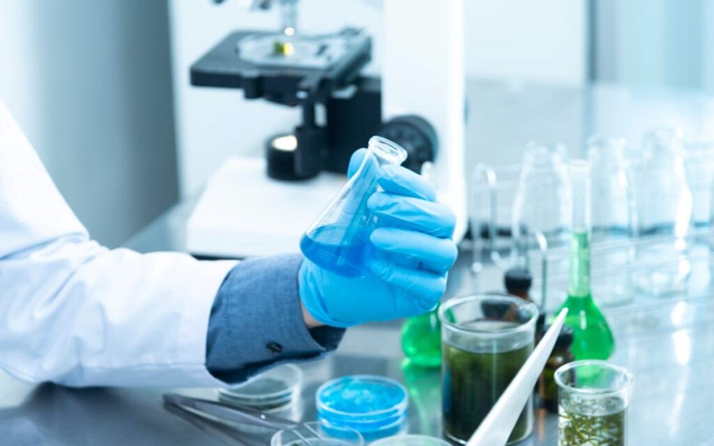 Person wearing gloves in a laboratory holding a test tube