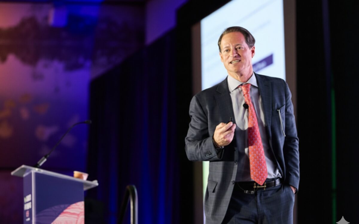 Phacilitate-header man in suit speaking to an audience on stage