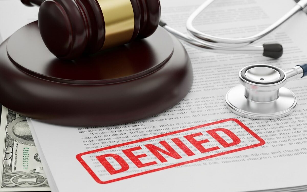 Authsnap-Denied-insurance-claims Conceptual image of a medical stethoscope, a legal gavel, and health insurance paperwork stamped with a red 'DENIED' mark, representing hospital revenue cycle strain.