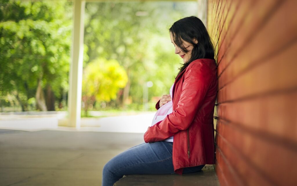 pregnant woman sitting against a wall