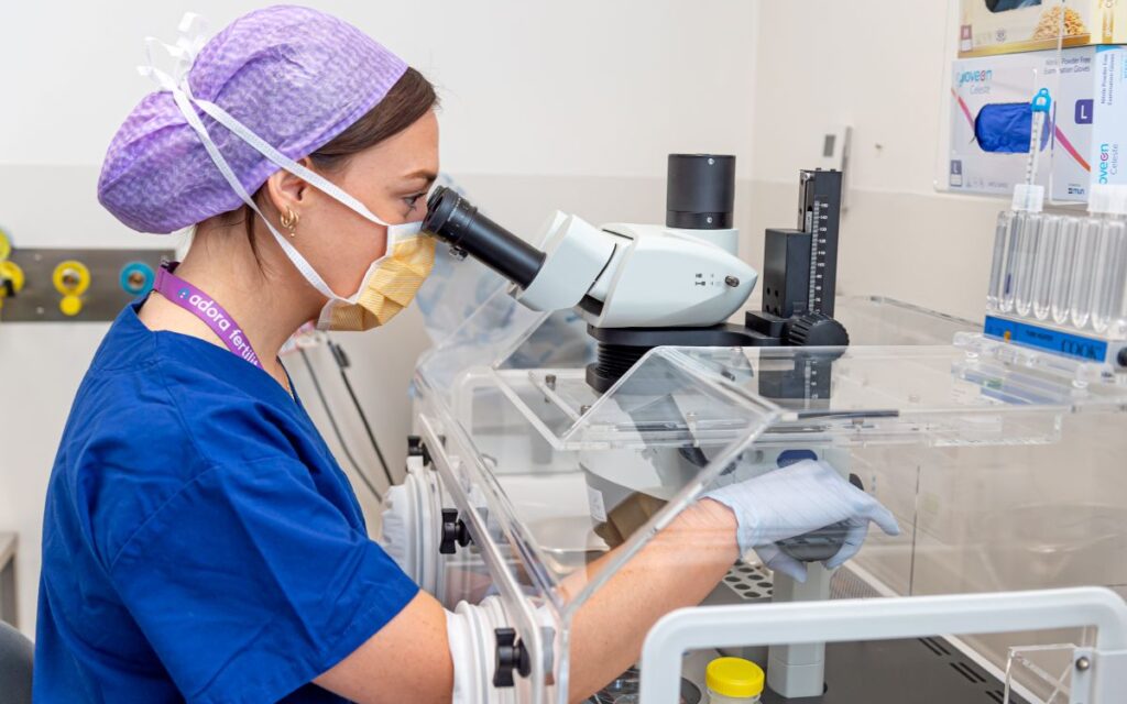 female lab technician looking through a microscope.