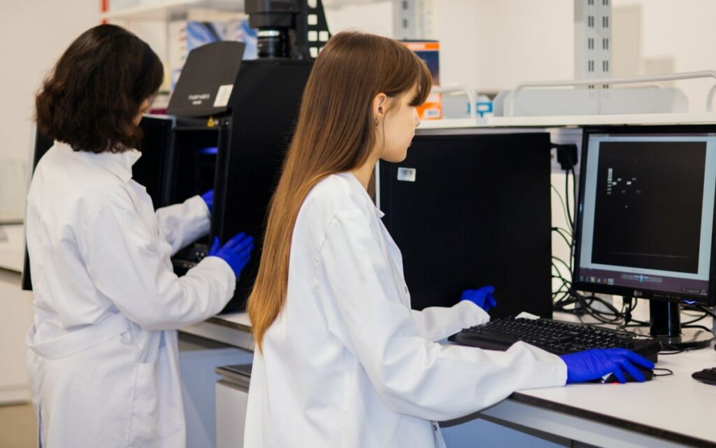 Two scientists reviewing clinical trial data security on a computer in a research lab