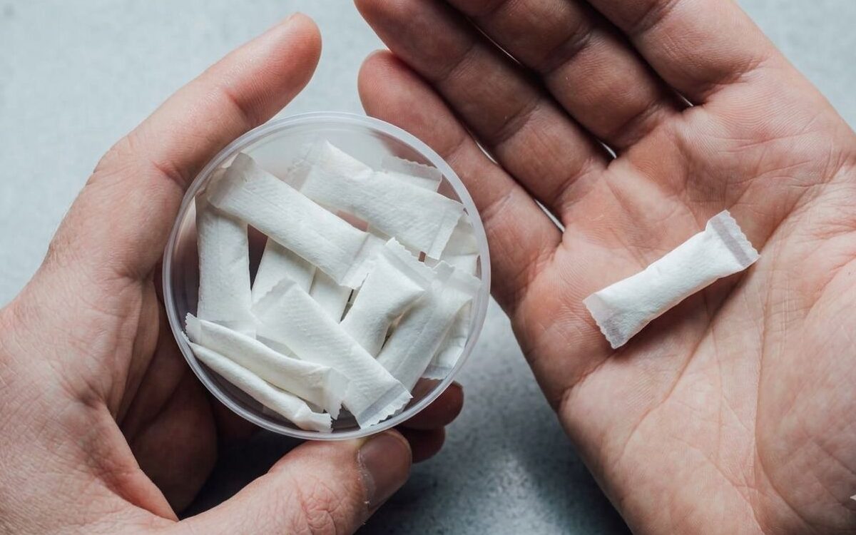 Hand holding a dish of nicotine pouches illustrating the PMTA landscape for nicotine pouches.