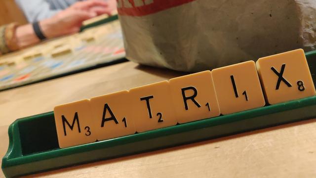 Scrabblebank mit den Buchstaben "MATRIX". Im Hintergrund wird gespielt