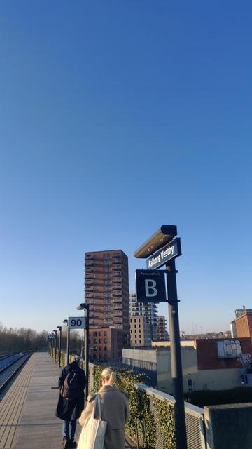 Sonne lässt einen Vororts-Bahnsteig gemütlich aussehen.