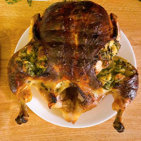 The chicken, resting on a plate. It's very brown and shiny, and the skin has pulled back from the slits I cut over the legs. You can see a hint of meat but it's mostly covered by lightly browned bread stuffing full of herbs