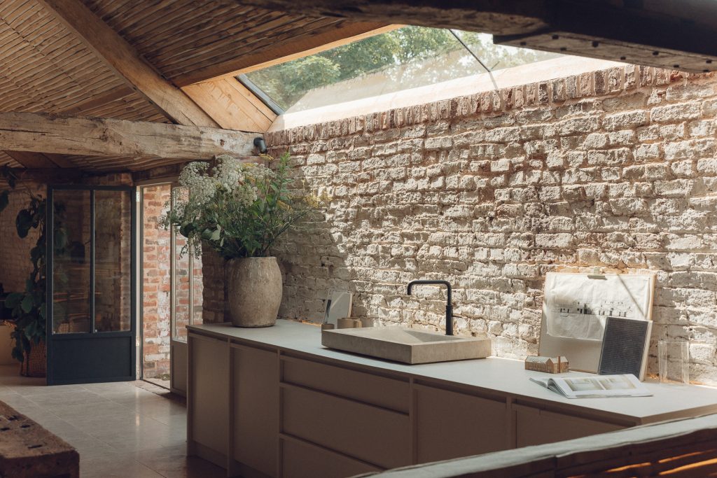 Kitchen with wooden units, exposed brick wall and ceiling window, decorated in 2025's 'textured' interior design trend.