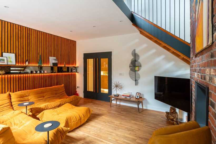 Maximalist living room with bold orange sofa and wood panel wall