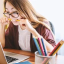 Woman biting pencil in front of computer