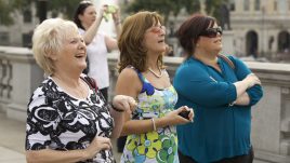 Three women gaze up at something off camera in varying stages of surprise.