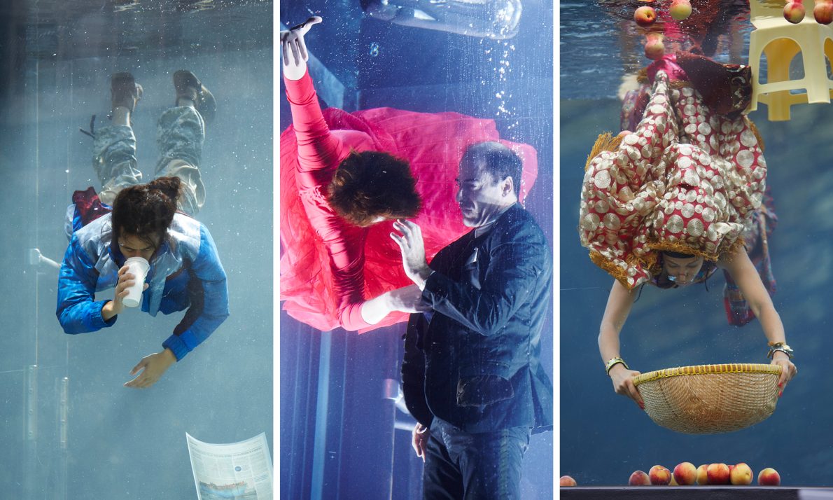Three underwater scenes L to R; a person in blue drinks from a disposable coffee cup surrounded by submerged newspapers; a woman in a red dress and a man in a smart jacket dance underwater; a person in colourful sari swims down with a basket to collects red apples at the bottom of the tank