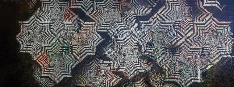 An intricate pattern of overlapping geometric shapes in black and white is projected onto a dark forest backdrop, creating a mesmerising, hypnotic effect.