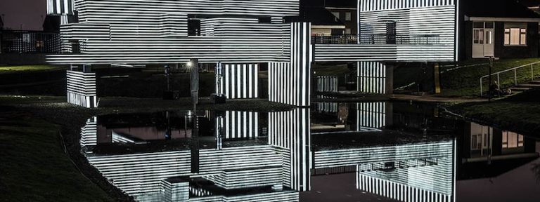Apollo Pavilion illuminated at night via projection in striped monochrome light.