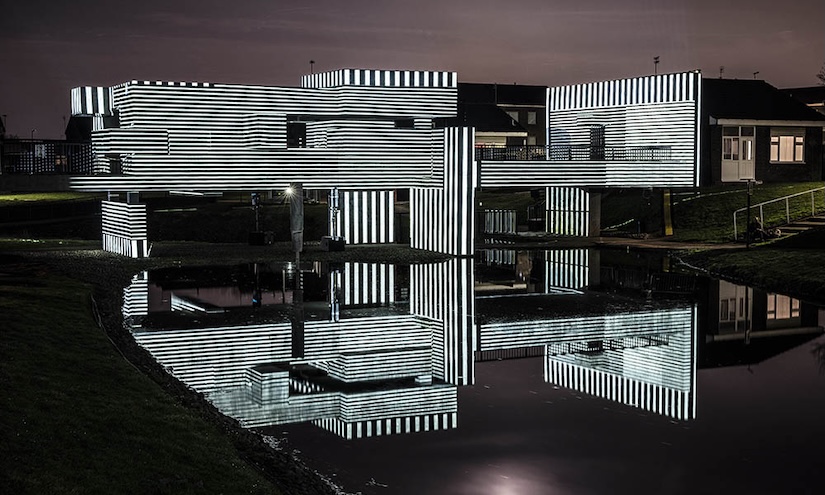 Apollo Pavilion illuminated at night via projection in striped monochrome light.