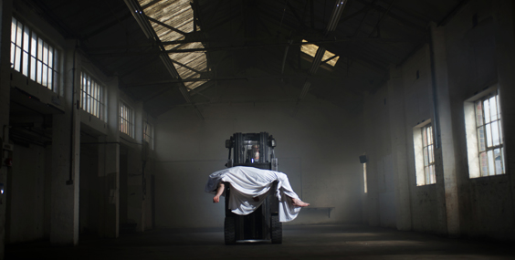 A human figure cloaked in a sheet and suspended from the roof of a warehouse. Stan's Cafe, Twilight of the Freaking Gods