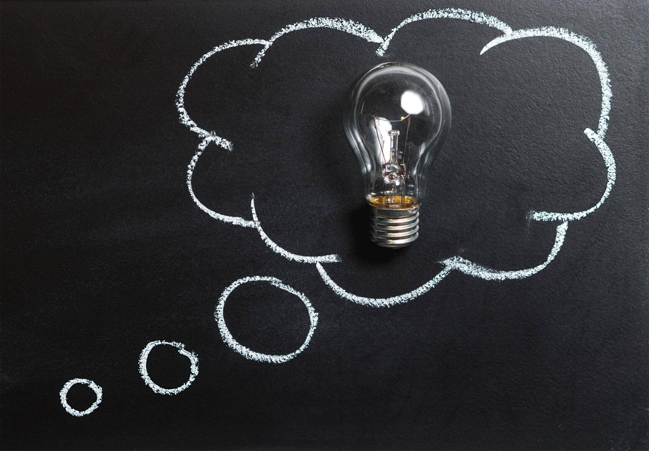 Light bulb on a blackboard with a thinking bubble drawn around it.