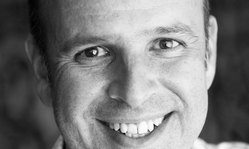 SebastianFrostBWlow-min A face-on headshot of Sebastian Frost in black and white. He is wearing a flowery shirt