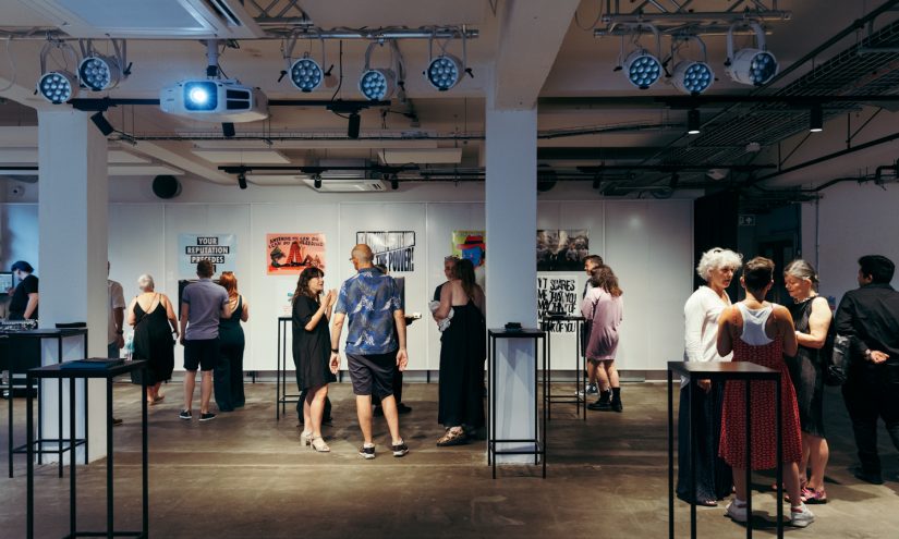 Wide shot of people mingling with artworks at The Gallery launch event.