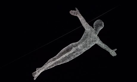 A light art installation in the shape of a figure with their arms outstretched. The figure is made out of glowing mesh and appears to be flying through the night sky