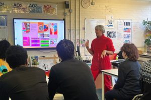 A tutor explains art techniques to students in a classroom.
