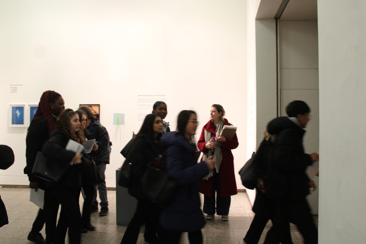 A group of students walk through a gallery in a blur.